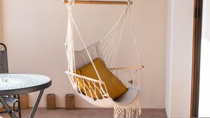 Ein Zimmer mit Hängesessel, einem runden Tisch und einer Tür.