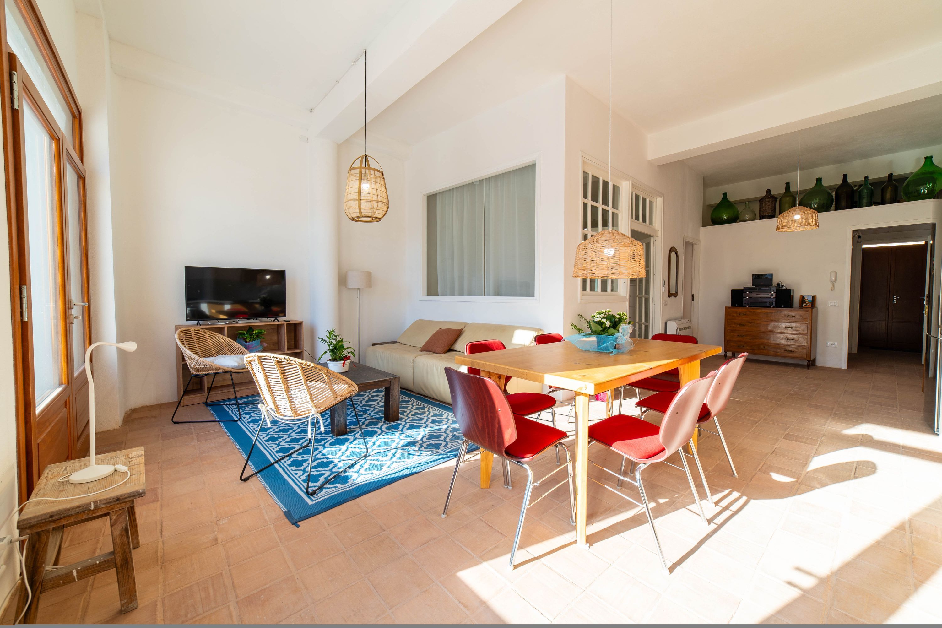 Un espacio habitable amplio con una mesa de comedor, sillas rojas, un sofá y un televisor.