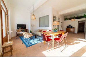 Un espacio habitable amplio con una mesa de comedor, sillas rojas, un sofá y un televisor.