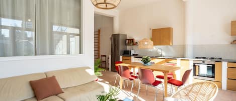 Una sala moderna con un sofá, una mesa de centro y un comedor con una mesa y sillas.