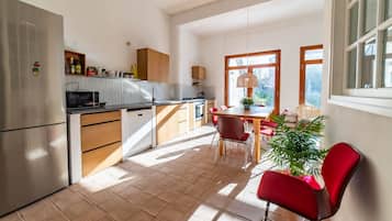 Cocina moderna con refrigerador, microondas y armarios de madera. Cuenta con un comedor con mesa y sillas, y una ventana que proporciona luz natural.