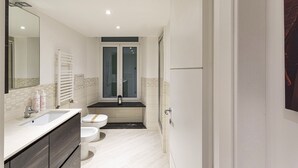 A modern bathroom with a white sink, two toilets, a large mirror, and a shower area. - Galea Studio by Wonderful Italy (Genoa)
