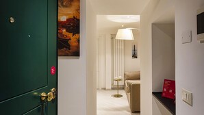 A hotel room with a green door, a painting of a cityscape, a lamp, and a bed. - Galea Studio by Wonderful Italy (Genoa)