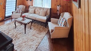A wooden-paneled room with a sofa, armchairs, and a coffee table.