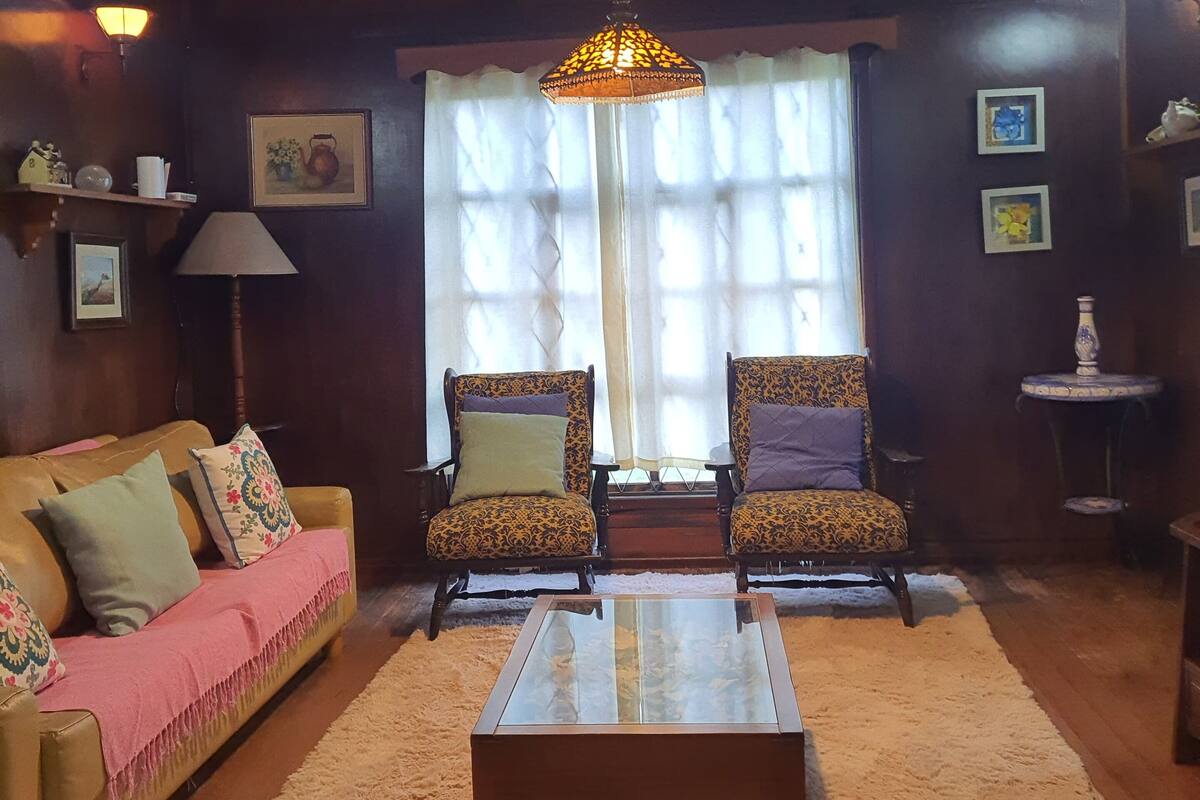 Una sala de estar acogedora con un sofá, dos sillones, una mesita de centro y una lámpara colgante.