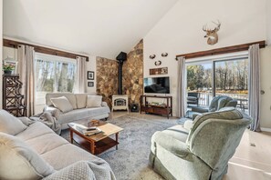 A living room with a stone wall, a fireplace, a television, and a deer head decoration. - Pet friendly home near Baileys Harbor, Door County (Baileys Harbor)