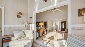 Ein Wohnzimmer mit gestreiften Sofas, einem Holztisch, einer Lampe und einem Deckenventilator.