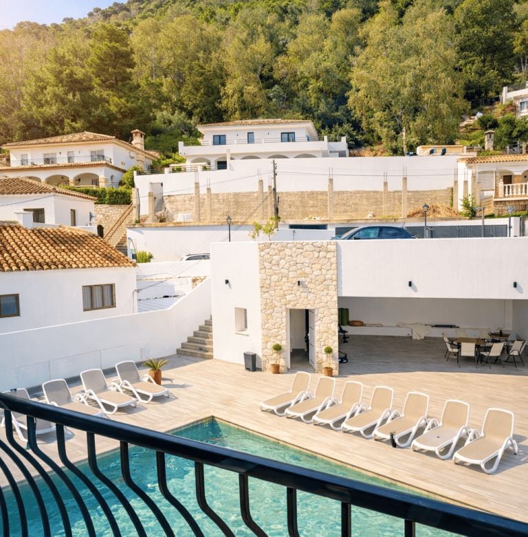 Un área de piscina con sillones de descanso y un muro de piedra.