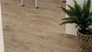 Une cuisine moderne avec un plan de travail noir, un évier et un petit îlot central. On y trouve également un coin repas avec un canapé et une table basse.