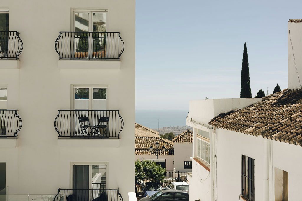 Un edificio de varios pisos con balcones, vistas al mar y techos de tejas tradicionales.