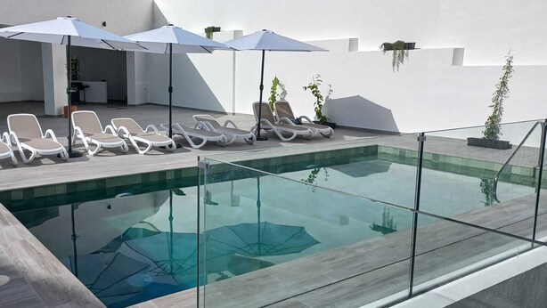 Un espace piscine extérieur moderne, doté de chaises longues et de parasols.