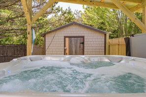 Un jacuzzi con una terraza de madera y un cobertizo pequeño al fondo.
