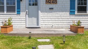 A white building with blue shutters and a door, marked with the number 415.