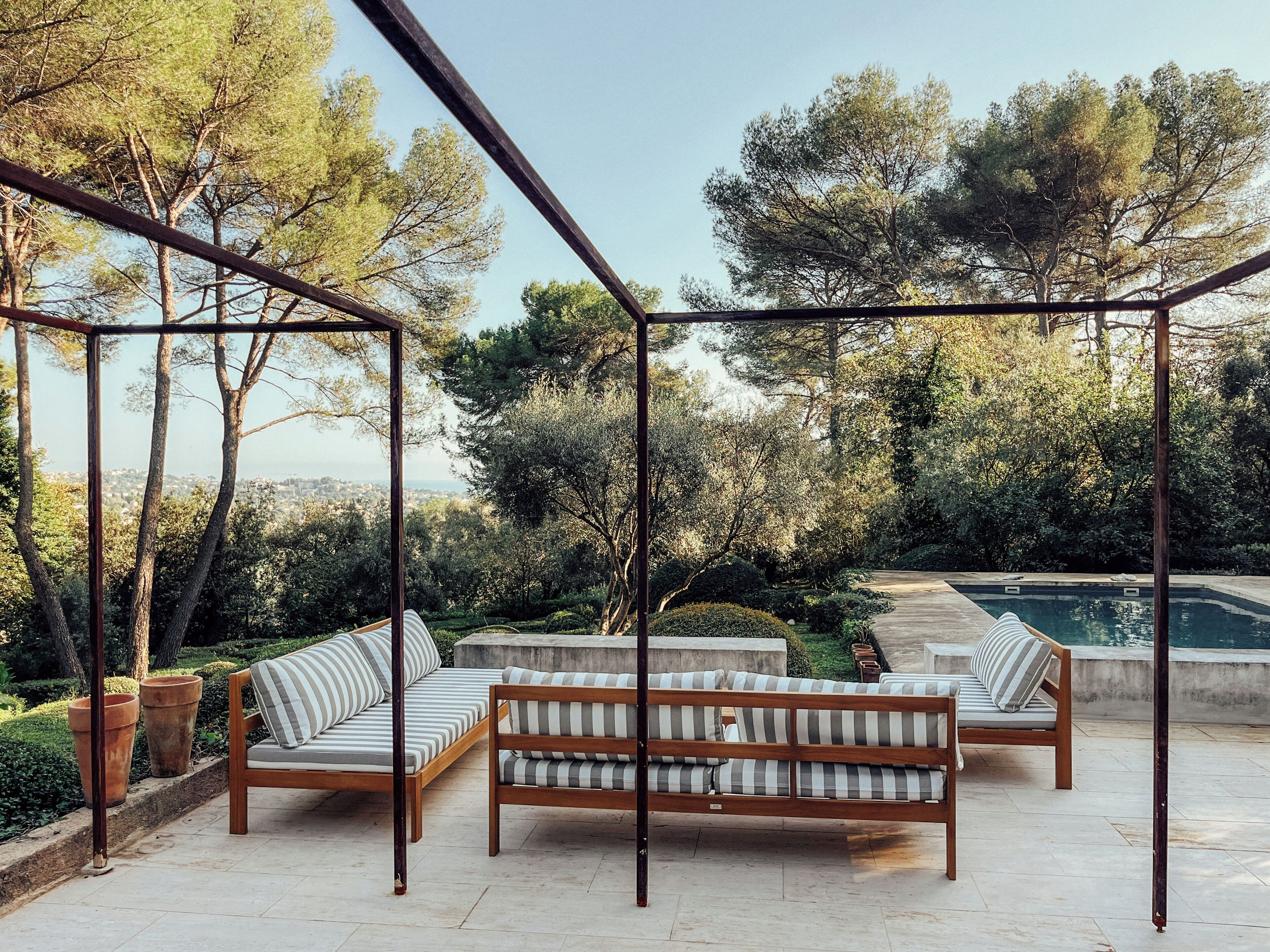 Une balançoire en bois avec des sièges rembourrés, une piscine et une vue sur le paysage urbain.