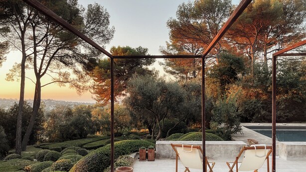 Eine Terrassenfläche mit einer Pergola, zwei Liegestühlen und Terrakottatöpfen.