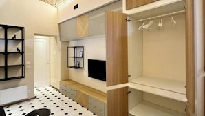 Une chambre moderne dotée d’une armoire intégrée, d’un petit coin salon et d’un téléviseur.