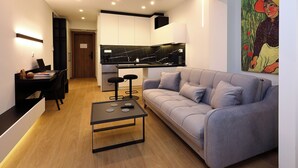 Ein modernes Wohnzimmer mit grauem Sofa, Couchtisch, Essbereich mit Laptop und Küche mit schwarzer Arbeitsplatte.