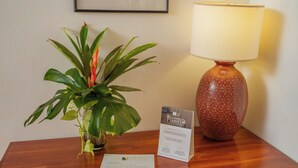 Una mesa de madera con una planta en maceta, una lámpara y un cartel.