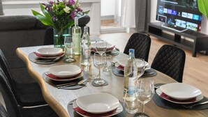 A dining table set with plates, glasses, and cutlery, with a vase of flowers and bottles of water. - VlNFUL2: Premium apartment | balcony | parking space (Mülheim an der Ruhr)