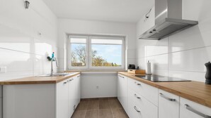A modern kitchen with white cabinets, wooden countertops, a window with a view, and a stainless steel range hood. - VlNFUL2: Premium apartment | balcony | parking space (Mülheim an der Ruhr)
