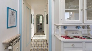 A hallway with patterned flooring, a white cabinet with glass doors, and a framed picture on the wall. - La Poetessa With Pool by Wonderful Italy (Camogli)