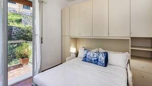 A bedroom with a bed, a nightstand, and a window with a view of a balcony and greenery. - La Poetessa With Pool by Wonderful Italy (Camogli)