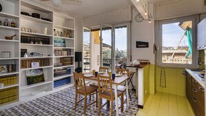 A dining area with a table and chairs, a bookshelf with various items, and a view through a window. - La Poetessa With Pool by Wonderful Italy (Camogli)