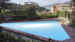 A rectangular swimming pool with a stone border, surrounded by a stone wall and a fence. - La Poetessa With Pool by Wonderful Italy (Camogli)
