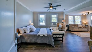 Une chambre à coucher avec un lit, une chaise, un canapé et un ventilateur de plafond.