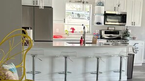 A modern kitchen with white cabinets, stainless steel appliances, and a central island with bar stools.