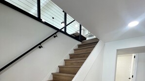 Eine Treppe mit Holzbodenstufen und weißen Wänden, die zu einem Raum mit Holzdielen führt.