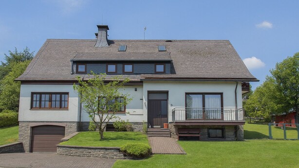 A two-story house with a garage, a small front yard, and a balcony.