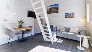 A modern interior with a loft bed, a dining area, a sofa, and artwork on the walls.