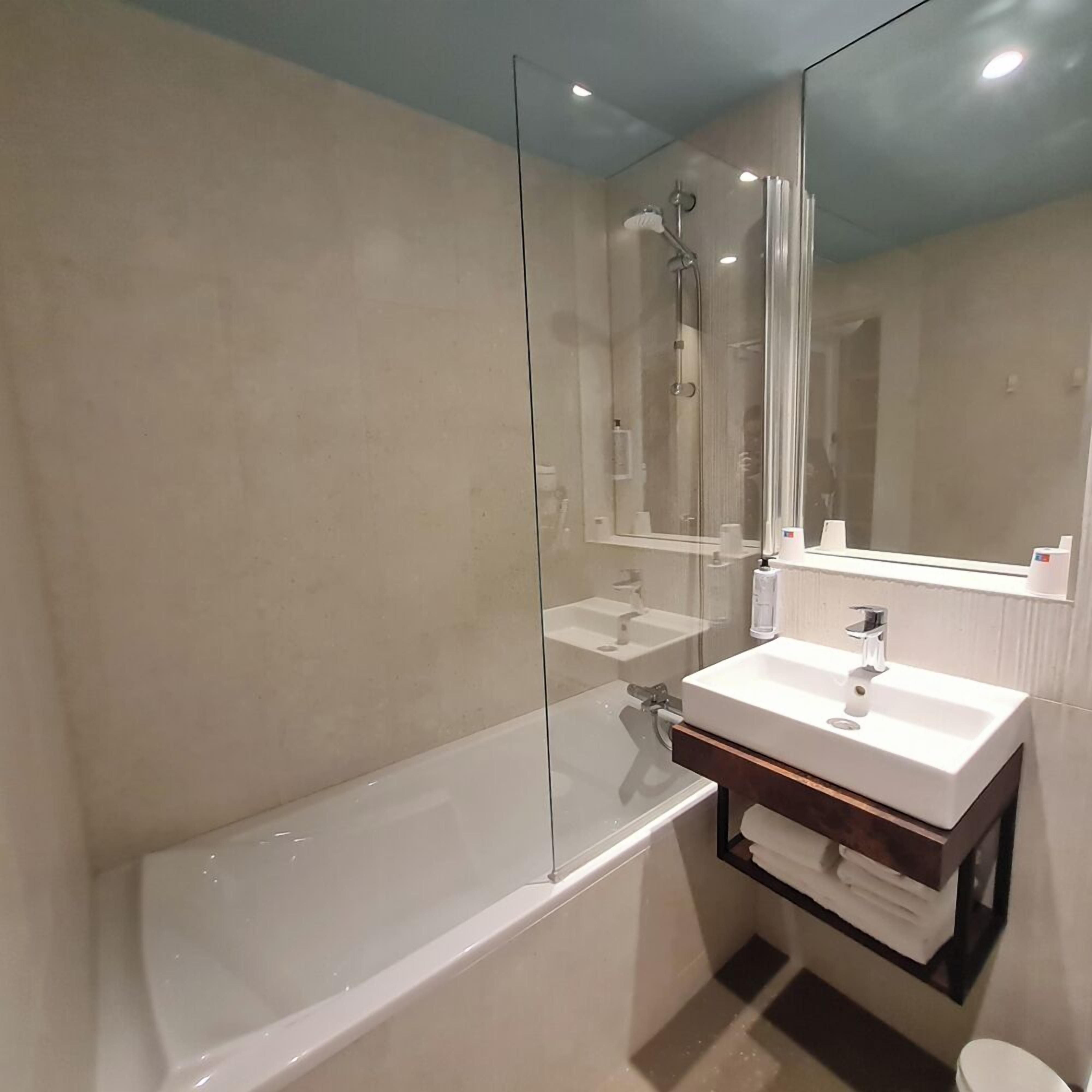 Une salle de bain moderne avec une douche à parois de verre, un lavabo blanc et un grand miroir.