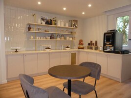 Una cocina moderna con armarios blancos, una mesa redonda con sillas y una cafetera.