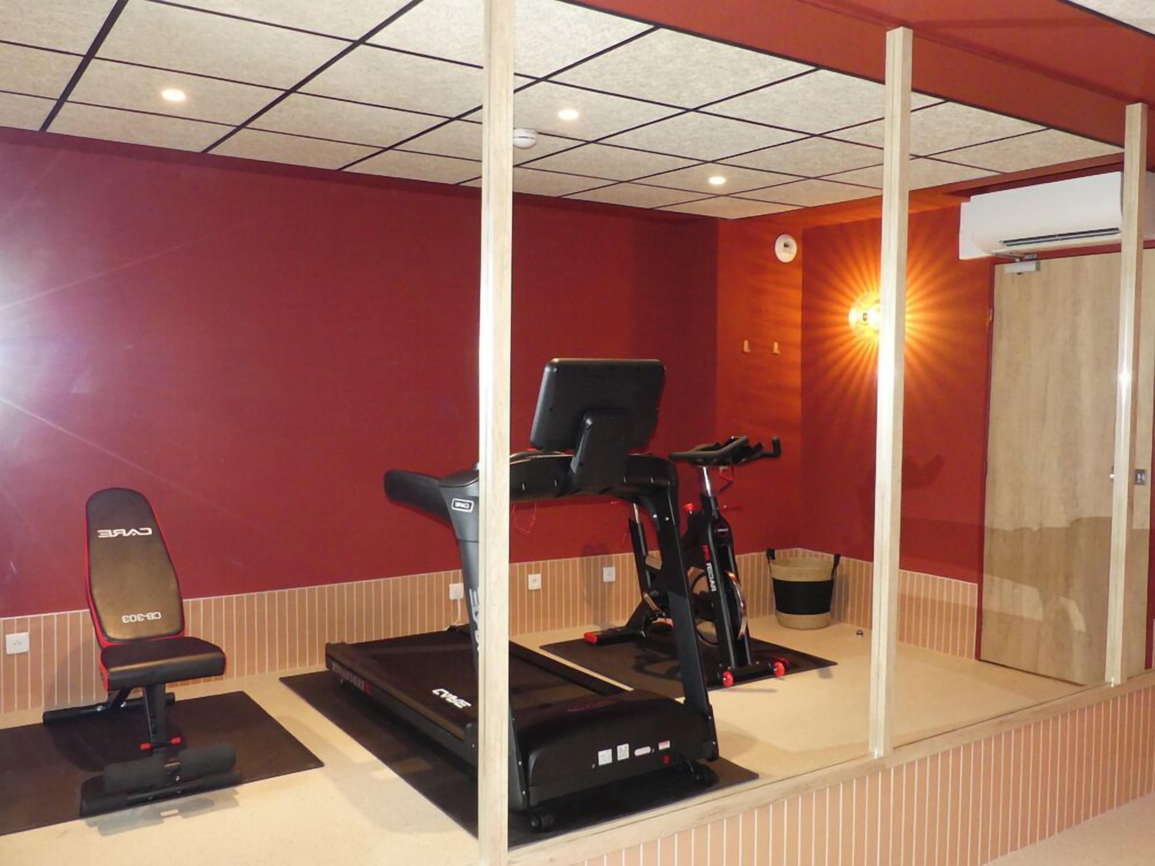 A gym with a treadmill, a stationary bike, and a weight bench.