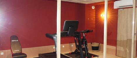 A gym with a treadmill, a stationary bike, and a weight bench.
