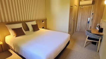 Een hotelkamer met een groot bed, een bureau en een douche.