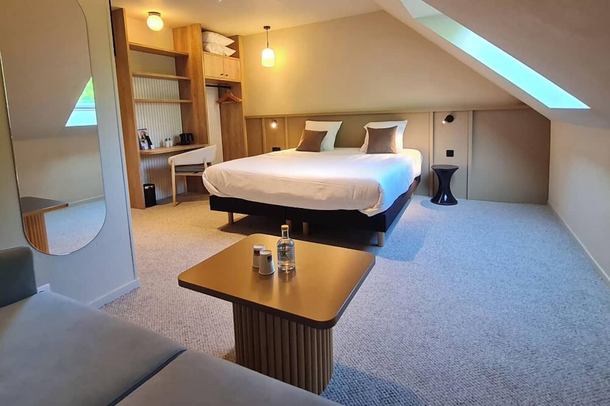 A modern bedroom with a large bed, a desk, a chair, and a small table with toiletries.