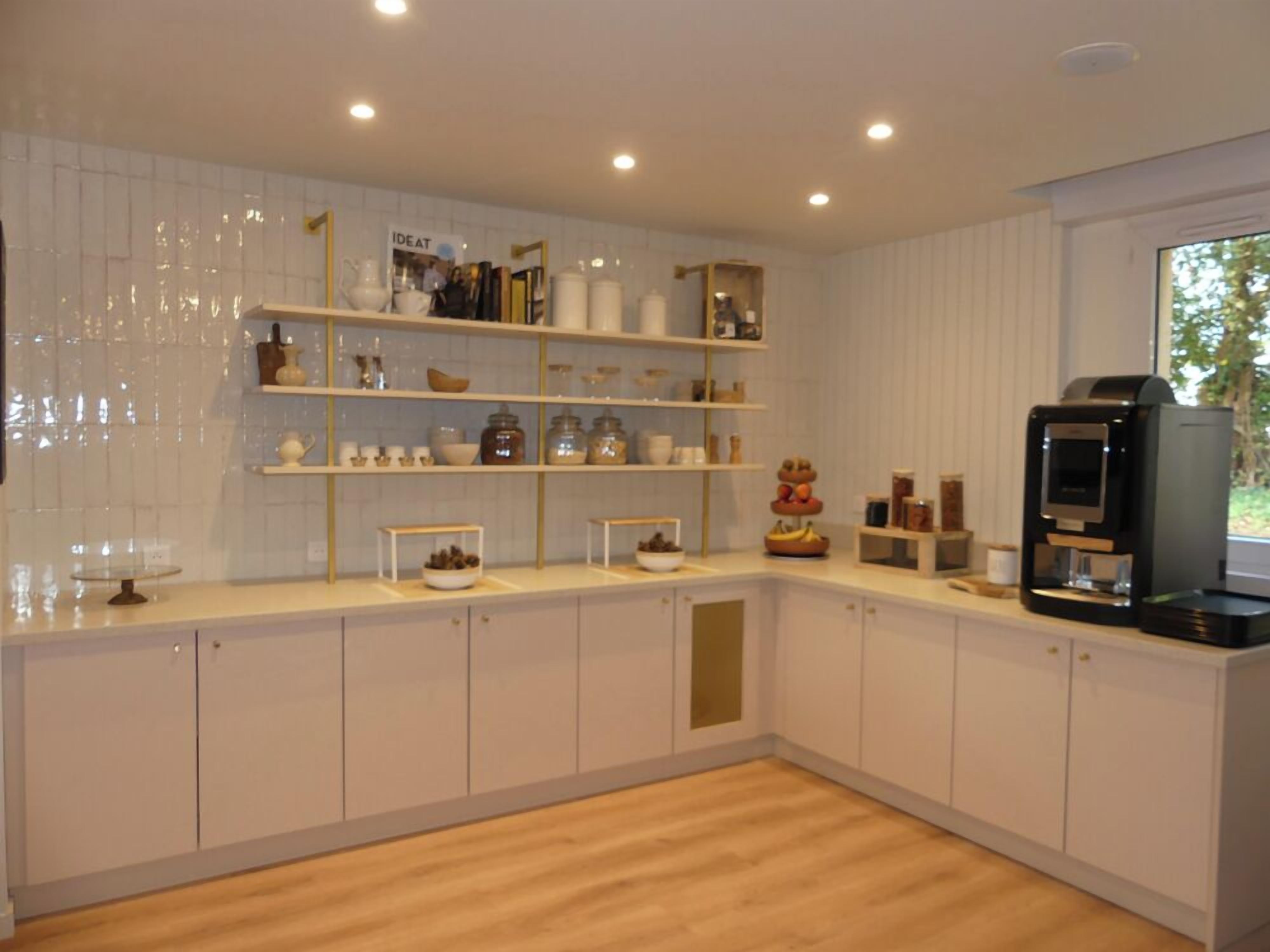A modern kitchen with white cabinetry, wooden countertops, and a built-in coffee machine.