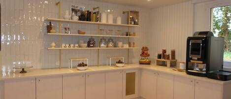 A modern kitchen with white cabinetry, wooden countertops, and a built-in coffee machine.