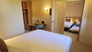 Een hotelkamer met een groot bed, een bureau met stoel, een kledingkast en een badkamer zichtbaar door een geopende deur.