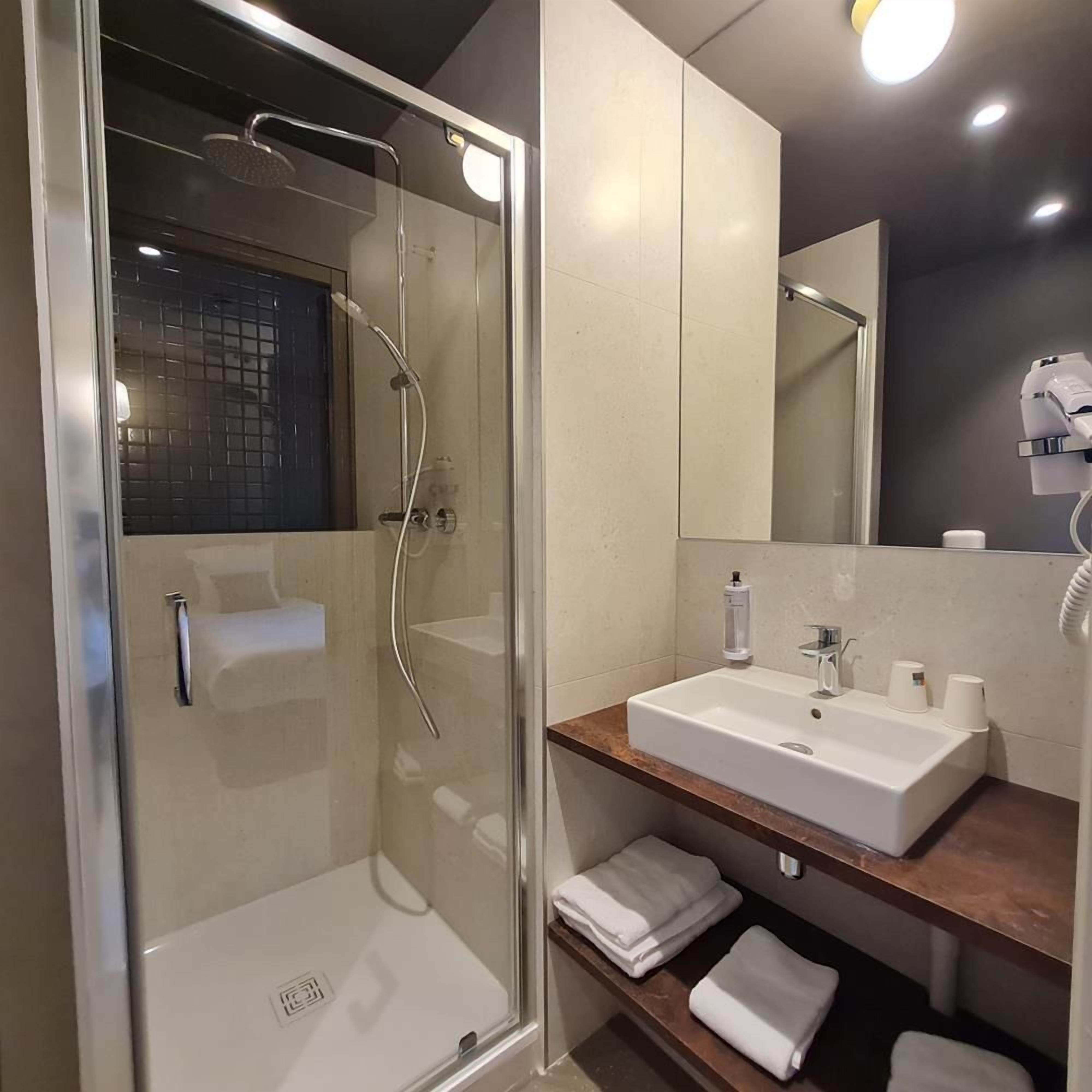 Une salle de bain moderne avec une douche à parois de verre, un lavabo blanc et un miroir au-dessus du lavabo.
