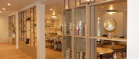 Un interior moderno con suelo de madera, muebles de almacenamiento con puertas de cristal y un comedor con sillas y mesas.