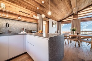 Enjoy meals in this kitchen with oven, sink, and dining area with wooden chairs and table.