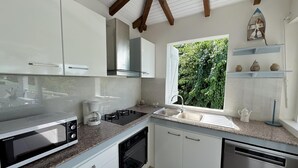 A modern kitchen with white cabinets, a built-in microwave, a gas stove, and a dishwasher. - Villa Fleur de Sel with swimming pool 5 minutes walk from the beach (le gosier)