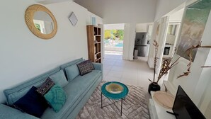 A living room with a sofa, a coffee table, and a TV. There is a kitchen in the background. - Villa Fleur de Sel with swimming pool 5 minutes walk from the beach (le gosier)