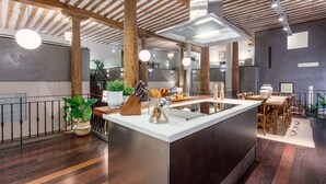 A modern kitchen with a central island, wooden beams, and a dining area with wicker chairs. - Historic Loft for 7 in Heart of Madrid (Madrid)