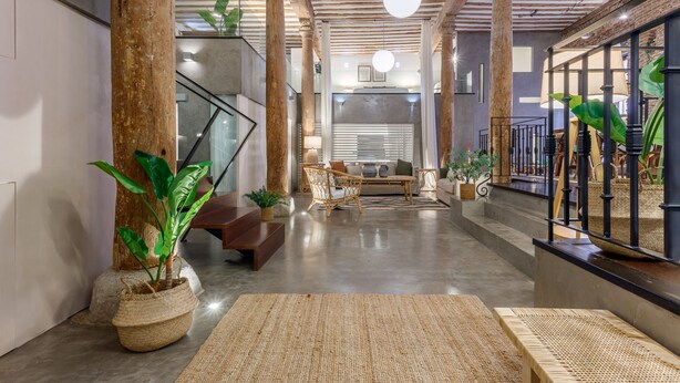 A spacious lobby with a high ceiling, exposed wooden beams, and a central staircase. There are several seating areas with cushions and a coffee table. - Historic Loft for 7 in Heart of Madrid (Madrid)