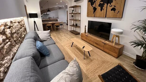 Un soggiorno moderno con un divano grigio, un tavolino in legno e una TV su un mobile in legno. Sul muro è presente una mappa del mondo e nell'angolo c'è una pianta.